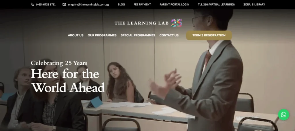 A screenshot of the homepage for The Learning Lab, featuring a main navigation menu at the top, contact information, and a central banner. The banner background shows a teacher gesturing towards students in a classroom setting, with overlaid text that reads "Celebrating 25 Years Here for the World Ahead." To the right, there is a brown button labeled "TERM 3 REGISTRATION."
