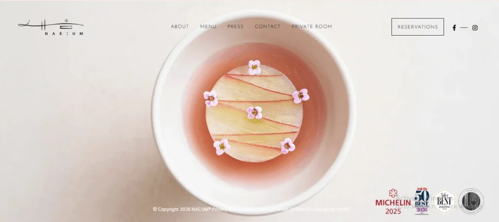 Website homepage of NAE:UM restaurant in Singapore featuring a minimalist fine-dining Korean dish garnished with small pink flowers.
