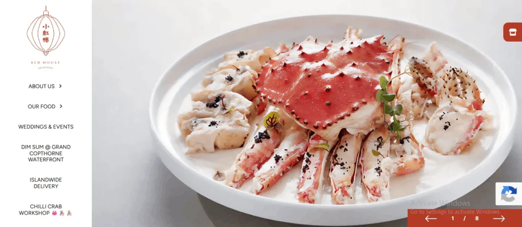 A large white platter featuring a cooked king crab dish from Red House Seafood, with a red carapace and legs arranged over a creamy white sauce, garnished with herbs and black seasoning. The left side displays a website navigation menu.