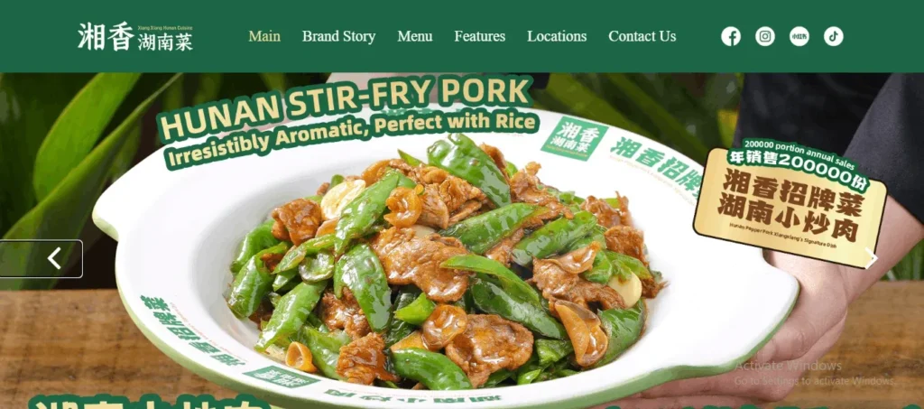 A website banner for Xiang Xiang Hunan Cuisine showcasing a large white bowl of Hunan Stir-Fry Pork with green peppers. The top navigation menu includes links like Main, Brand Story, Menu, and Locations against a dark green background.