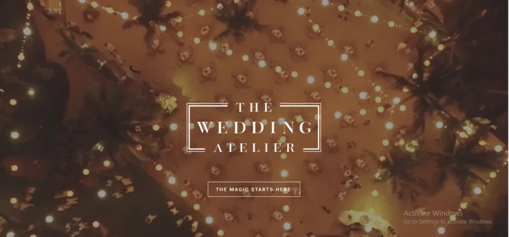 An overhead view of an outdoor evening wedding reception with warm fairy lights and palm trees, featuring the logo for 'The Wedding Atelier' and a button reading 'The magic starts here'.