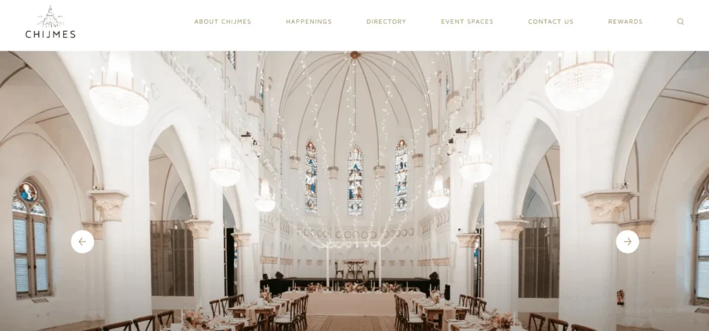 Website screenshot of the CHIJMES Hall wedding venue in Singapore, featuring a beautifully decorated white gothic-style chapel interior with high ceilings, chandeliers, and stained-glass windows set up for a banquet.